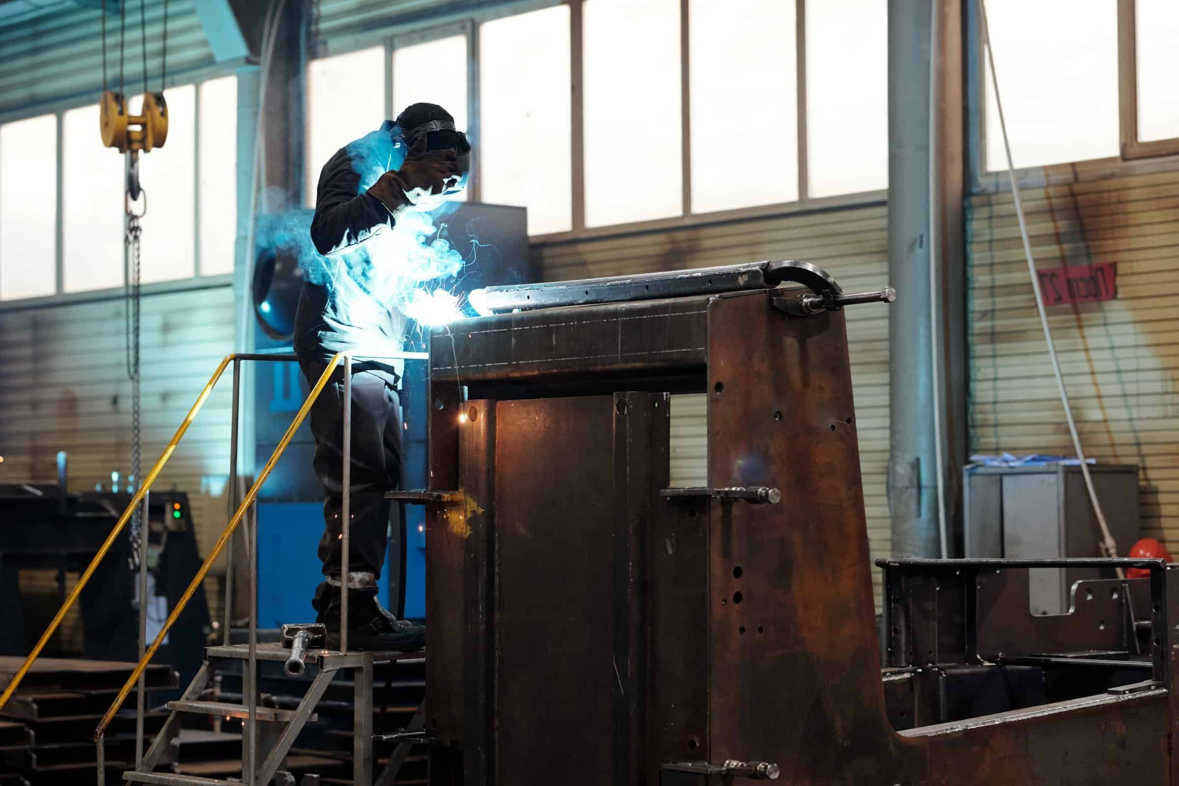 keenworx worker or welder in protective mask and uniform using arc welding repairing industrial machine flipped